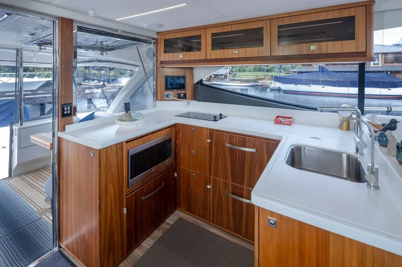 Slide: The Image of Luxurious 2023 Riviera 505 SUV yacht kitchen with modern appliances and elegant wood cabinetry. - 8