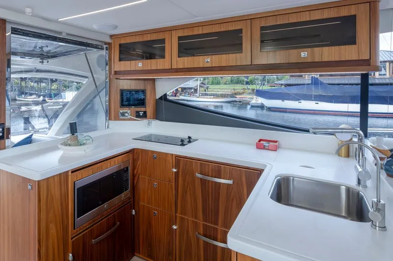 Slide: The Image of Modern kitchen interior of 2023 Riviera 505 SUV yacht with wood cabinetry and waterfront view. - 9