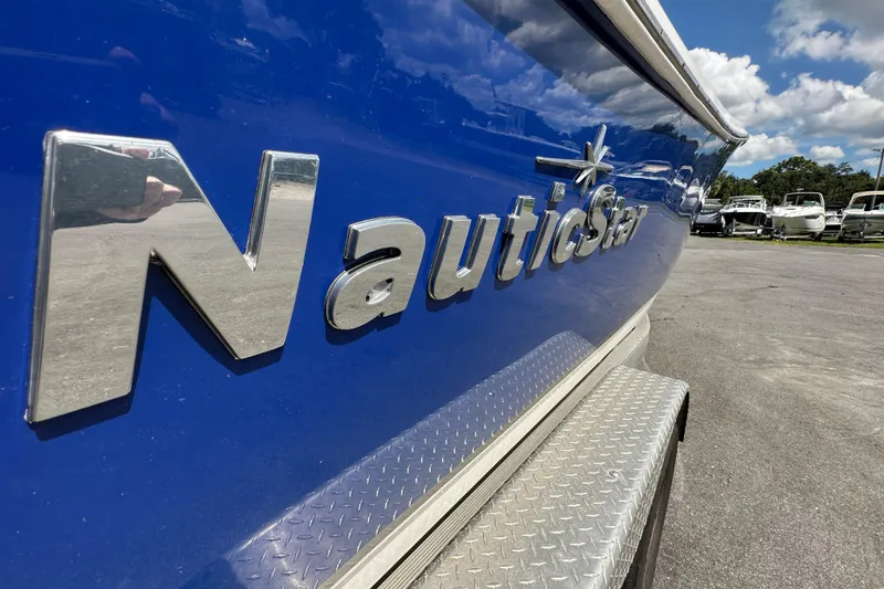 Slide: The Image of 2020 NauticStar 2302 Legacy boat with blue hull and chrome logo in a marina. - 2