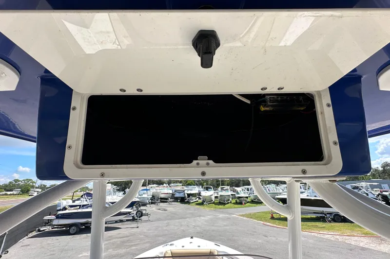 Slide: The Image of 2020 NauticStar 2302 Legacy boat storage compartment, open with visible interior, in a marina setting. - 28