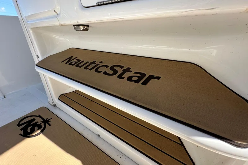 Slide: The Image of NauticStar 2302 Legacy 2020 boat step with logo, featuring teak-style design. - 39