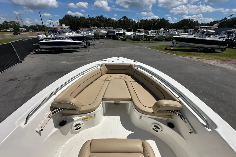 Slide: The Image of 2020 NauticStar 2302 Legacy boat with tan seating, parked among other boats under a blue sky. - 47