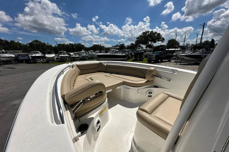 Slide: The Image of 2020 NauticStar 2302 Legacy boat with beige seating, parked under a partly cloudy sky. - 48