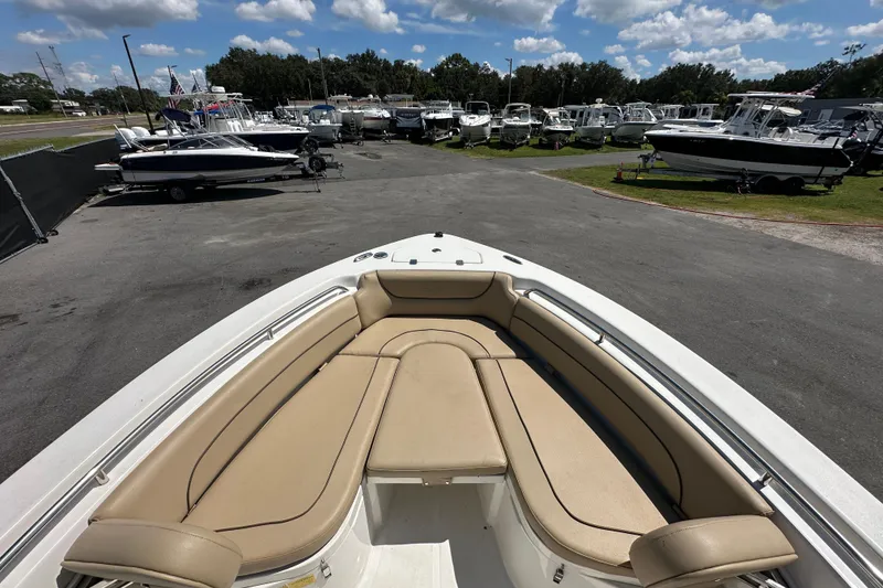 Slide: The Image of 2020 NauticStar 2302 Legacy boat with tan seating, parked among other boats under a blue sky. - 50