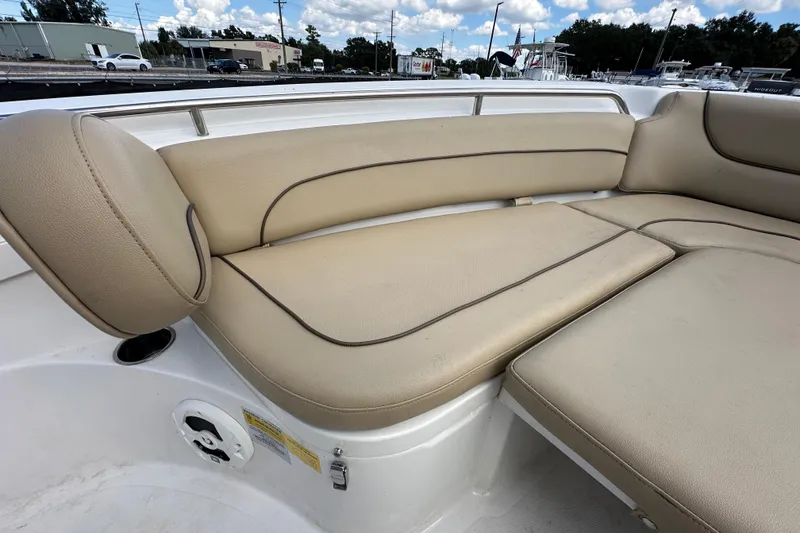 Slide: The Image of 2020 NauticStar 2302 Legacy boat with beige cushioned seating, outdoor setting. - 53