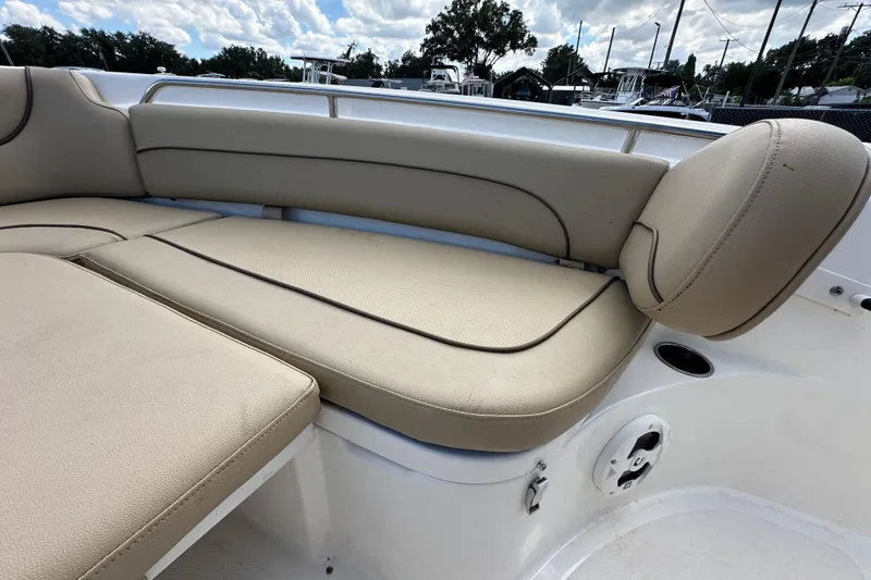 Slide: The Image of 2020 NauticStar 2302 Legacy boat with beige cushioned seating under a cloudy sky. - 56