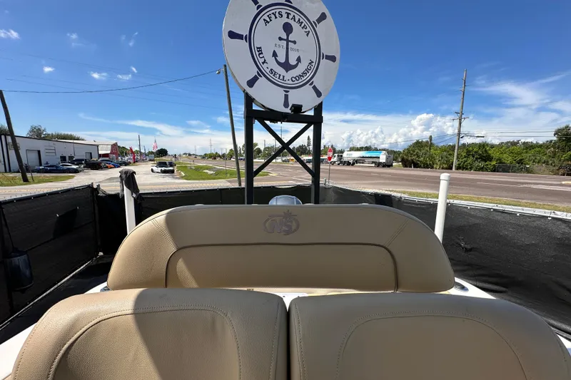 Slide: The Image of 2020 NauticStar 2302 Legacy boat with tan seats, parked near a road under a clear blue sky. - 80