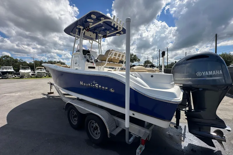 Slide: The Image of 2020 NauticStar 2302 Legacy boat with Yamaha engine on trailer under cloudy sky. - 9
