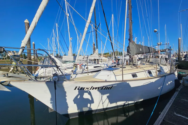 The Image of 1979 Fast Passage 39 sailboat docked in marina, named "Rushwind," with clear blue sky. - 0