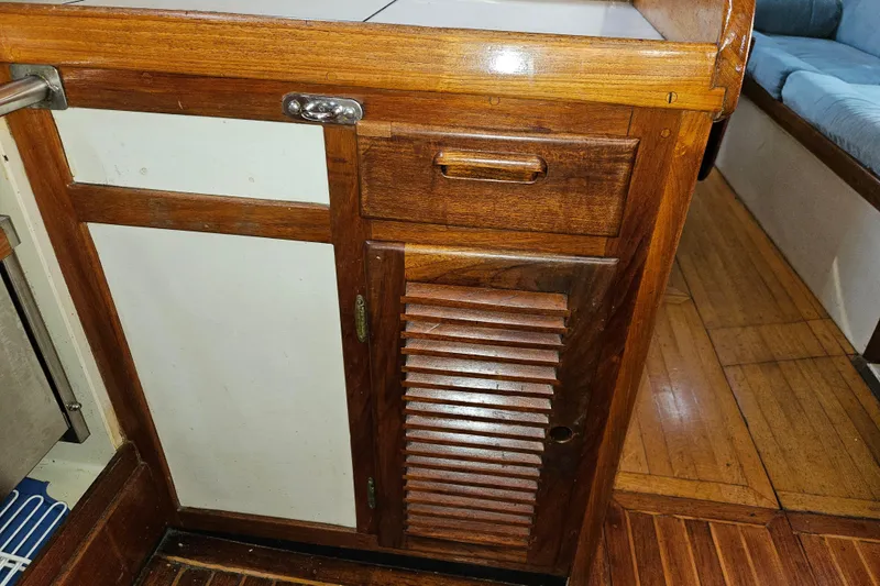 Slide: The Image of Wooden interior of 1979 Fast Passage 39 sailboat, featuring cabinets and flooring. - 26