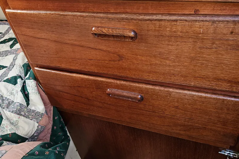 Slide: The Image of Wooden drawers on a 1979 Fast Passage 39 sailboat, next to a patterned quilt. - 32