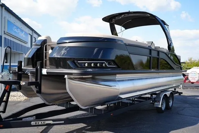 Slide: The Image of 2026 Harris Grand Mariner 250 pontoon boat on trailer, sleek design, black exterior, sunny day. - 2