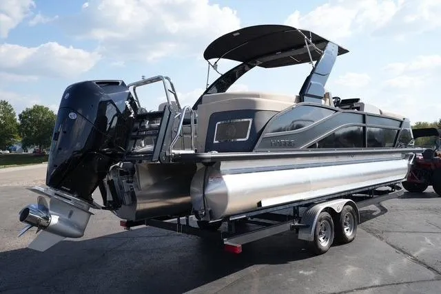 Slide: The Image of 2026 Harris Grand Mariner 250 pontoon boat on trailer, featuring sleek design and powerful outboard motor. - 5