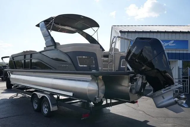 Slide: The Image of 2026 Harris Grand Mariner 250 pontoon boat on trailer, featuring sleek design and powerful outboard motor. - 7