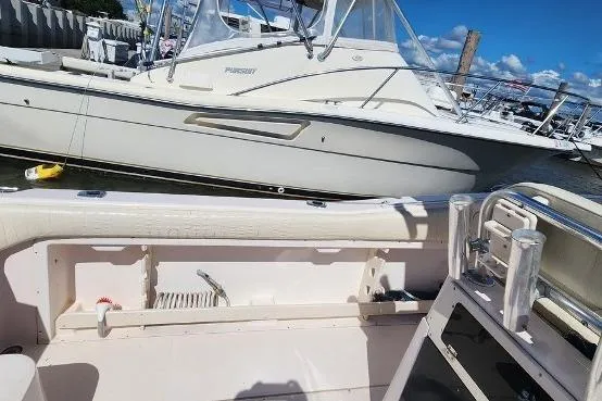 Slide: The Image of 1999 Grady-White Advance 247 boat docked, featuring spacious deck and fishing rod holders. - 18