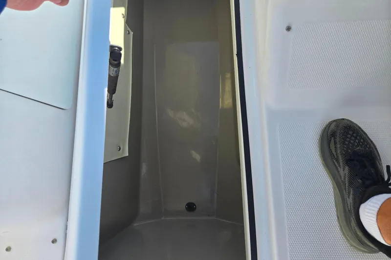 Slide: The Image of 2013 Yamaha Boats 242 Limited S interior with foot on deck, showing storage compartment. - 15