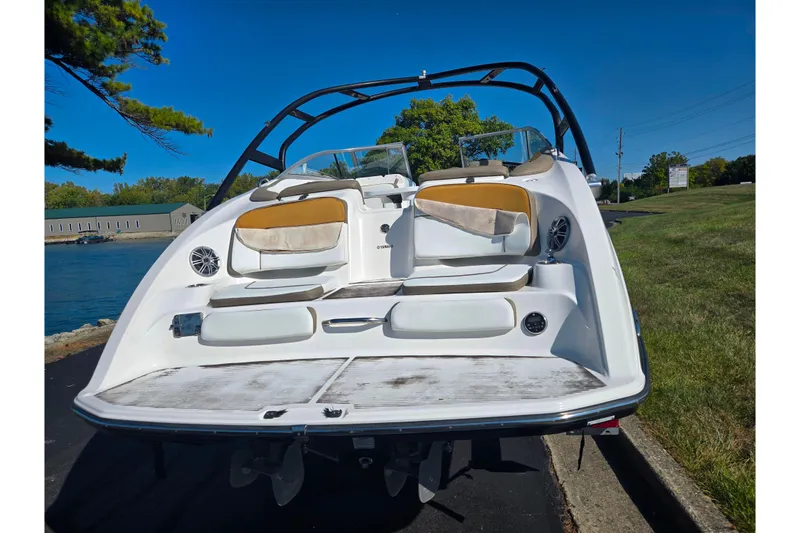 Slide: The Image of 2013 Yamaha Boats 242 Limited S, rear view, docked by a scenic waterfront. - 2