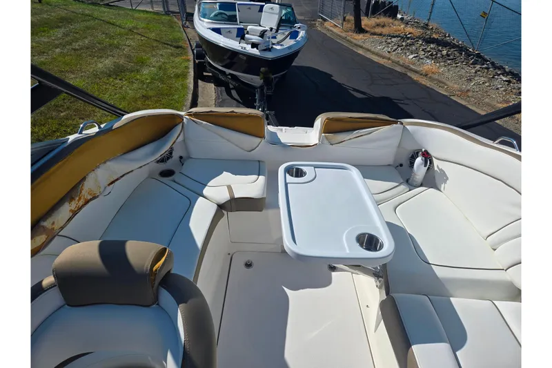Slide: The Image of 2013 Yamaha Boats 242 Limited S interior with seating and table, docked near water. - 24