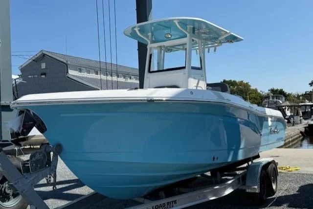 Slide: The Image of 2023 NauticStar 242L Offshore boat on trailer, light blue hull, dockside view. - 1