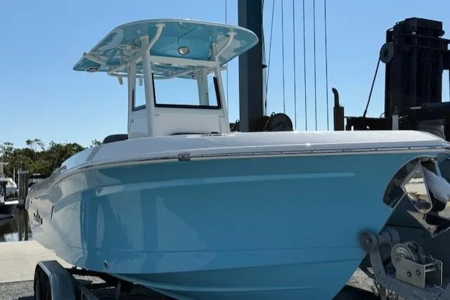 Slide: The Image of 2023 NauticStar 242L Offshore boat with blue hull on trailer, dockside view. - 2