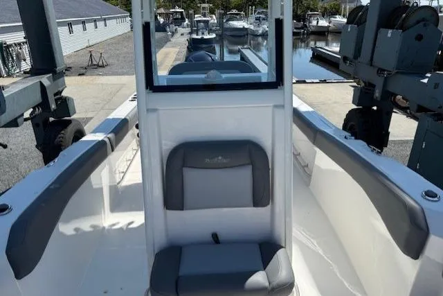 Slide: The Image of 2023 NauticStar 242L Offshore boat interior with gray seating at a marina. - 9
