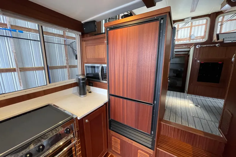 Slide: The Image of Interior of 2021 American Tug 362, featuring a modern kitchen with wood cabinetry. - 13