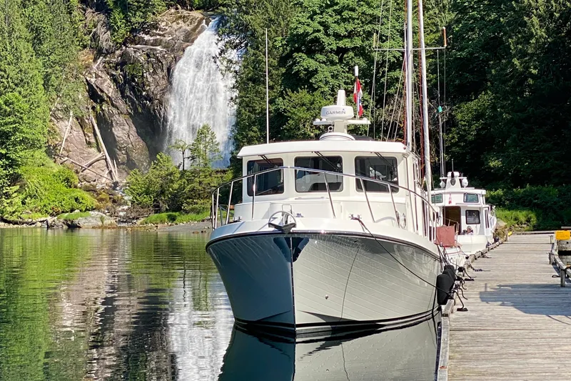 Slide: The Image of American Tug 362 (2021) docked near a scenic waterfall and lush greenery. - 2