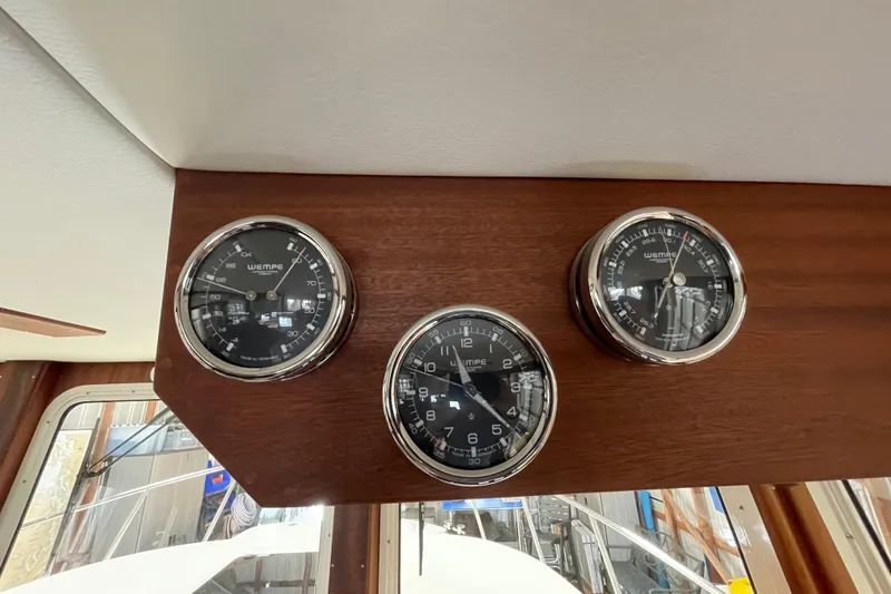 Slide: The Image of Gauges on 2021 American Tug 362 boat dashboard, featuring wooden panel and nautical instruments. - 26