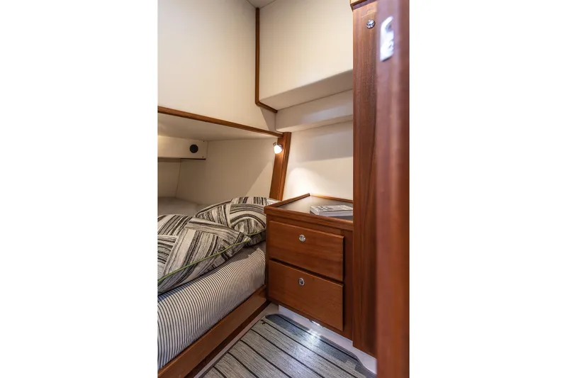 Slide: The Image of Cozy cabin interior of 2021 American Tug 362 with wooden drawers and striped bedding. - 44
