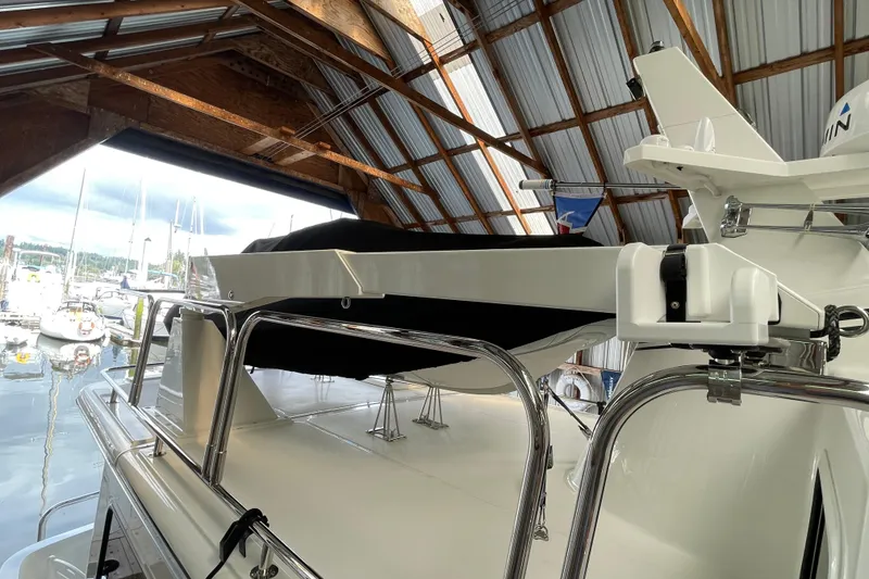 Slide: The Image of 2021 American Tug 362 in a marina, under a wooden roof, with boats in the background. - 55