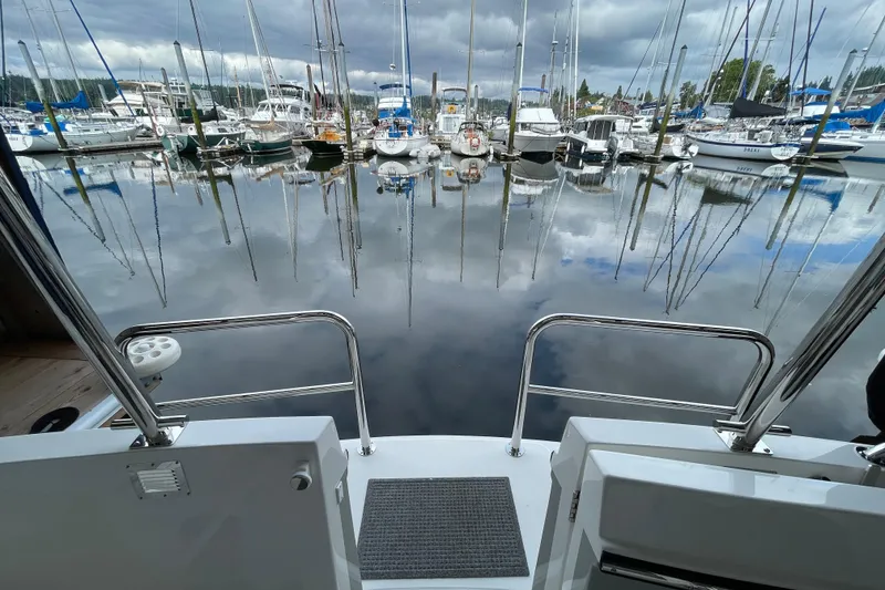 Slide: The Image of American Tug 362 (2021) at marina, surrounded by sailboats and calm water reflections. - 60