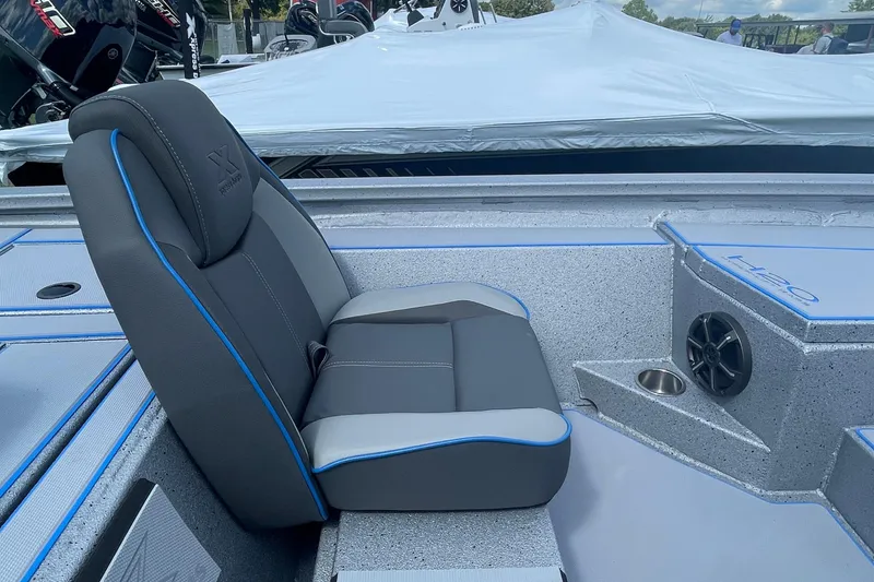 Slide: The Image of 2026 Xpress H20 Bass boat interior with gray and blue seating, speaker, and cup holder. - 7