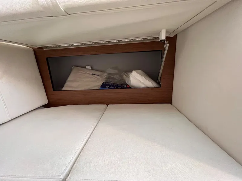 Slide: The Image of 2019 Cruisers Yachts 338 IO interior storage compartment with cushions and wooden trim. - 34