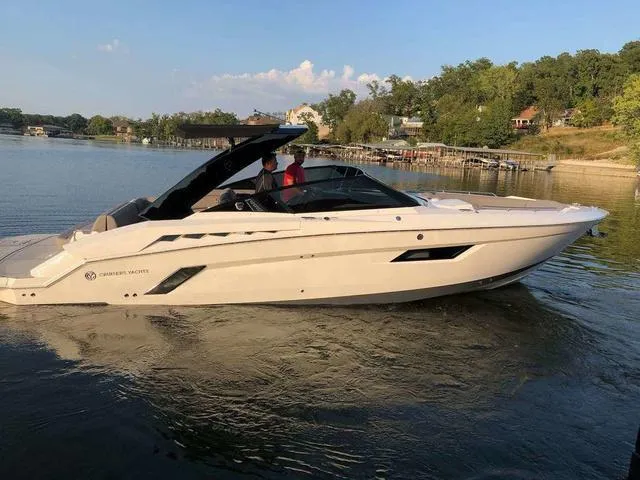 Slide: The Image of 2019 Cruisers Yachts 338 IO on a serene lake, surrounded by lush greenery. - 58
