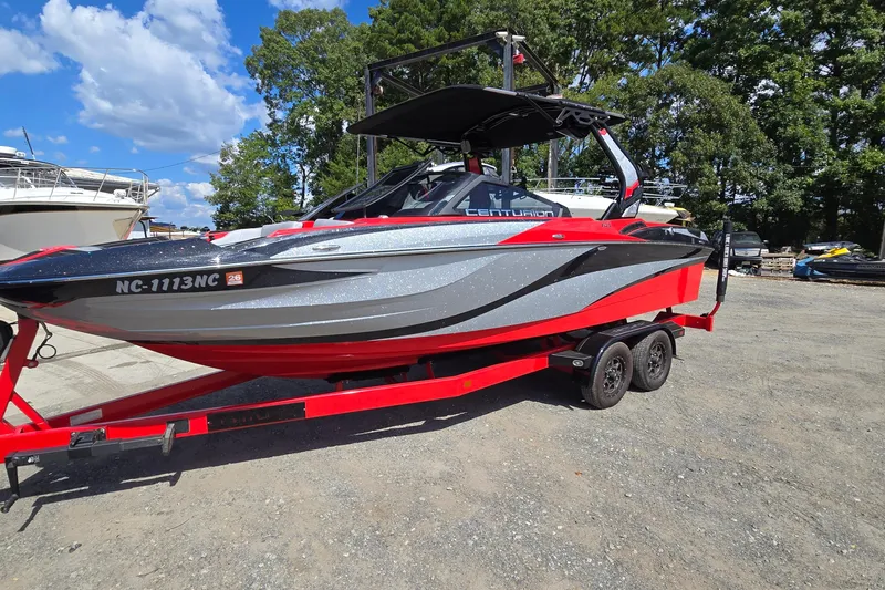 The Image of 2022 Centurion Fi23 boat on red trailer, parked outdoors under blue sky. - 0