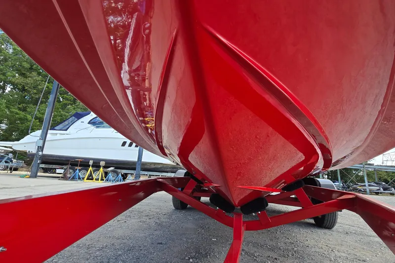 Slide: The Image of Red 2022 Centurion Fi23 boat on trailer, parked outdoors near other boats. - 15