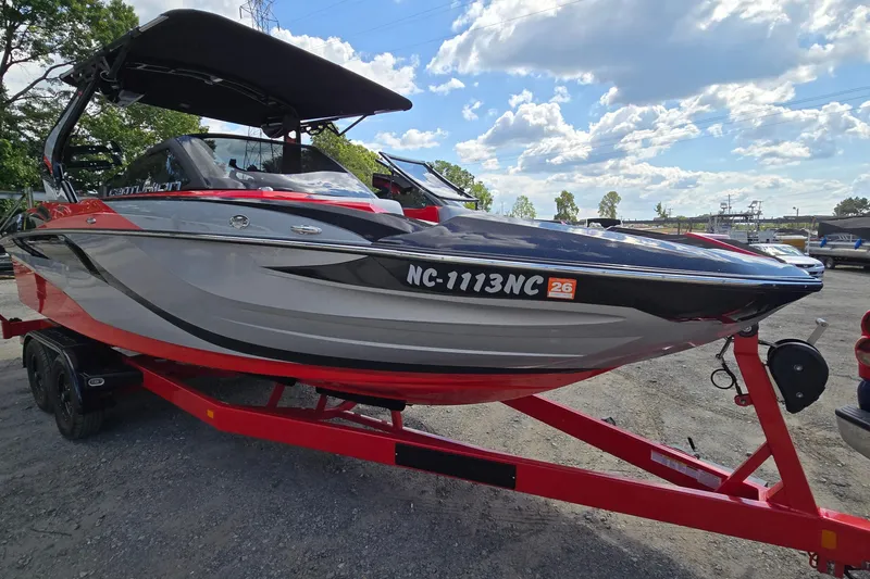 Slide: The Image of 2022 Centurion Fi23 boat on red trailer under blue sky. - 2