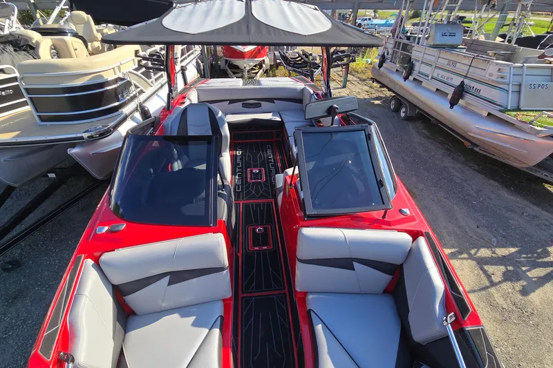 Slide: The Image of 2022 Centurion Fi23 boat with red exterior and gray seating, docked among other boats. - 55