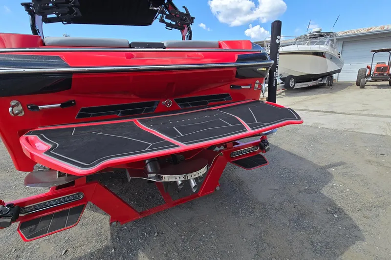 Slide: The Image of 2022 Centurion Fi23 boat with red exterior and black detailing, parked outdoors. - 6