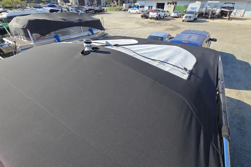 Slide: The Image of 2022 Centurion Fi23 boat with black cover in a marina parking area. - 97