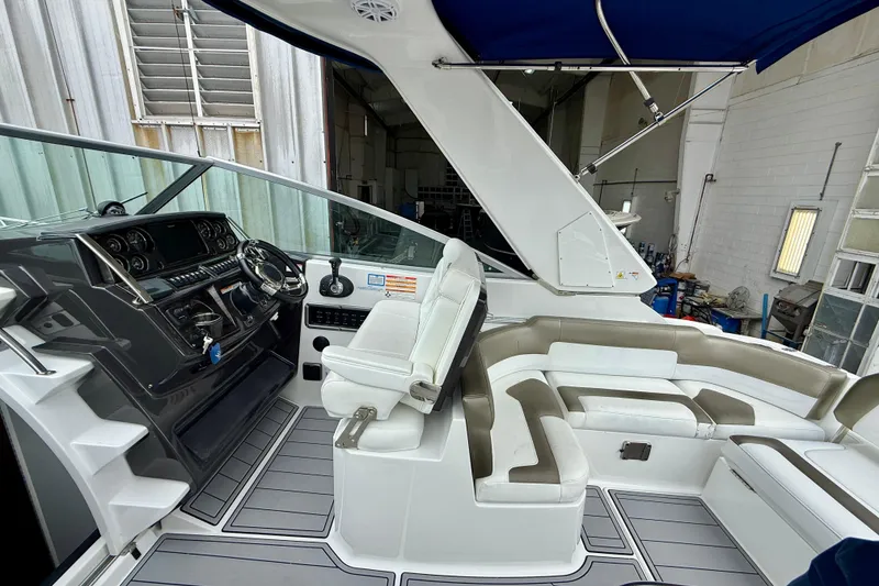 Slide: The Image of 2019 Monterey 295 Sport Yacht interior with helm, seating, and canopy in a workshop setting. - 12