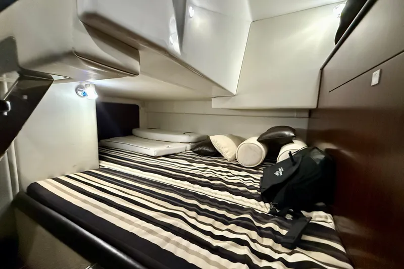 Slide: The Image of 2019 Monterey 295 Sport Yacht cabin with striped bedding and cushions. - 21