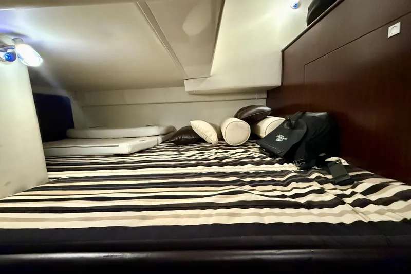 Slide: The Image of Cozy cabin interior of 2019 Monterey 295 Sport Yacht with striped bedding and cushions. - 22
