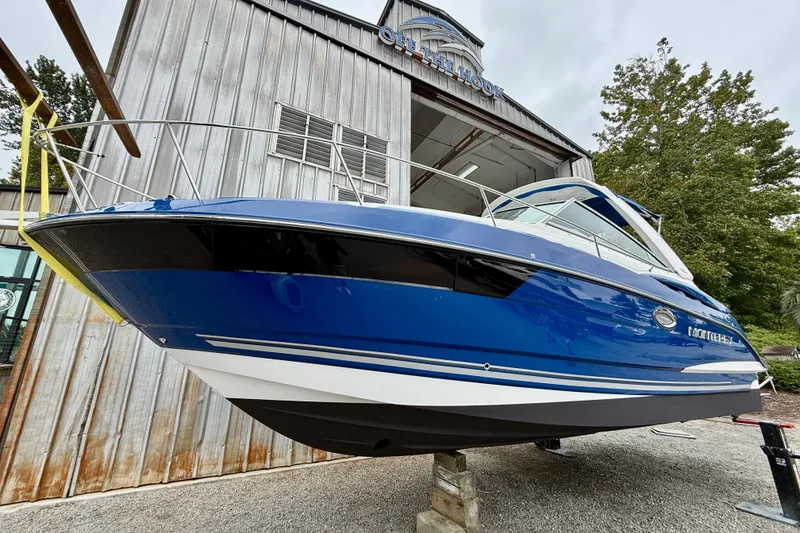 Slide: The Image of 2019 Monterey 295 Sport Yacht in blue, displayed outside a wooden building. - 3