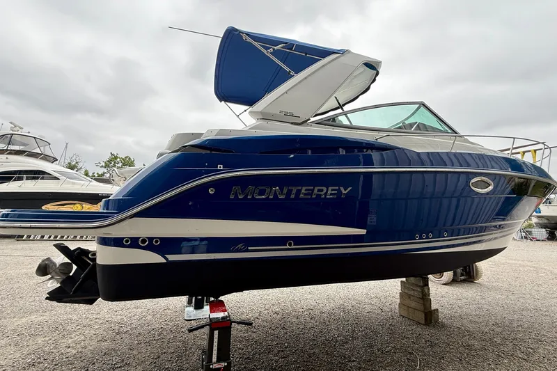 Slide: The Image of 2019 Monterey 295 Sport Yacht in blue, displayed on a stand outdoors. - 4