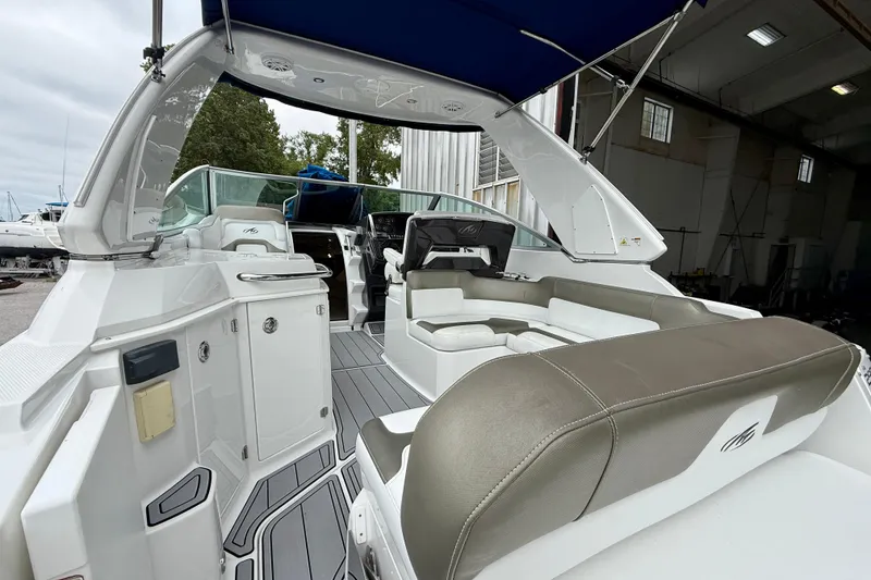Slide: The Image of 2019 Monterey 295 Sport Yacht interior with seating, under a blue canopy, docked indoors. - 9