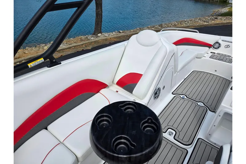 Slide: The Image of 2020 Hurricane SunDeck Sport 202 IO interior with red and white seating, near a lake. - 12