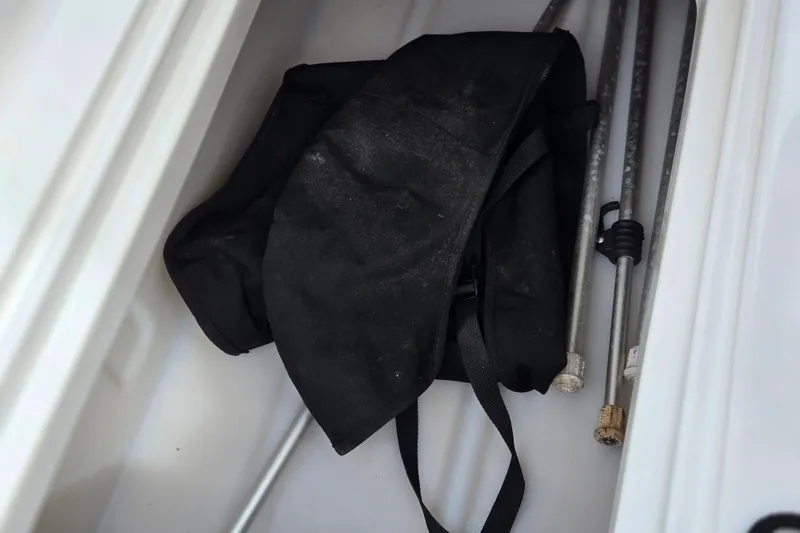 Slide: The Image of Storage compartment of 2020 Hurricane SunDeck Sport 202 IO with black bag and metal rods. - 16