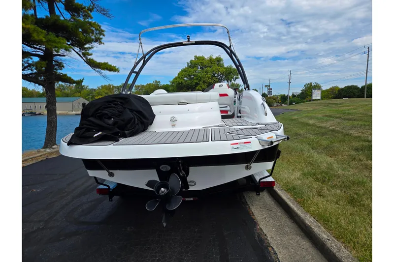 Slide: The Image of 2020 Hurricane SunDeck Sport 202 IO boat parked near a lake under a cloudy sky. - 2