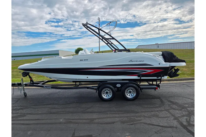 Slide: The Image of 2020 Hurricane SunDeck Sport 202 IO boat on trailer, parked outdoors under cloudy sky. - 4